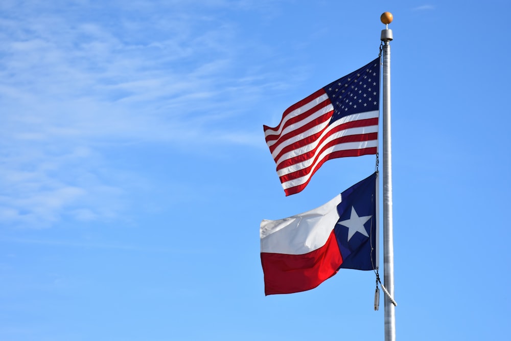 two american and texas flags waving in the wind
