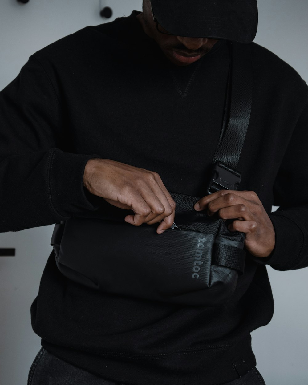 a man in a black hoodie holding a black camera bag