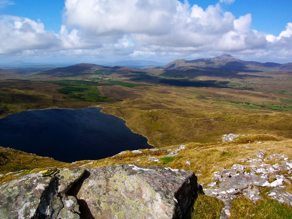 a view of a lake and mountains from the top of a hill