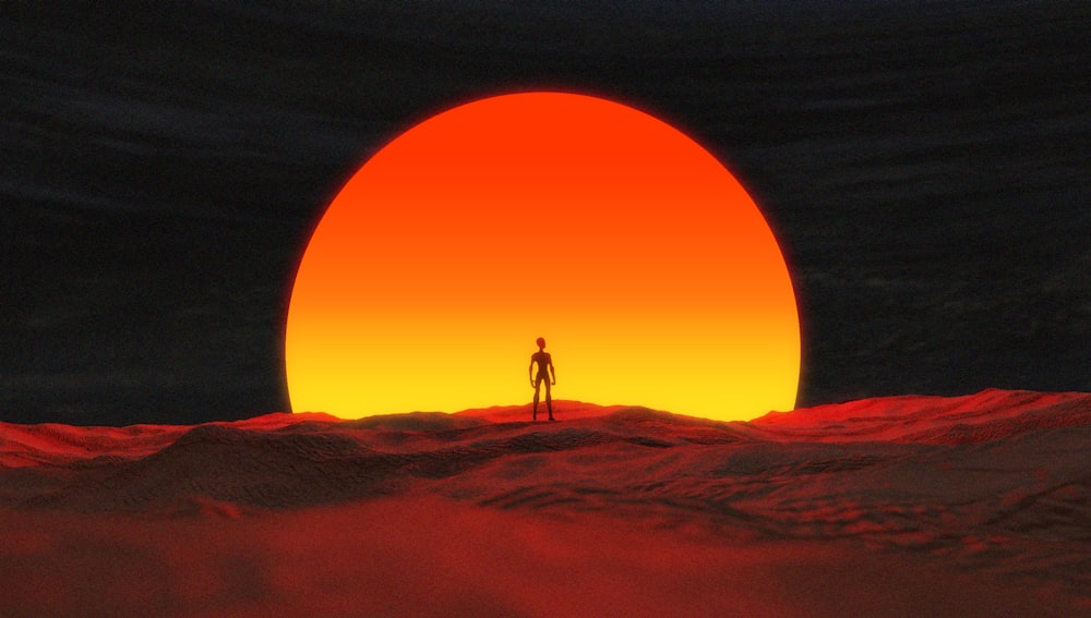um homem de pé no topo de um deserto sob um sol vermelho