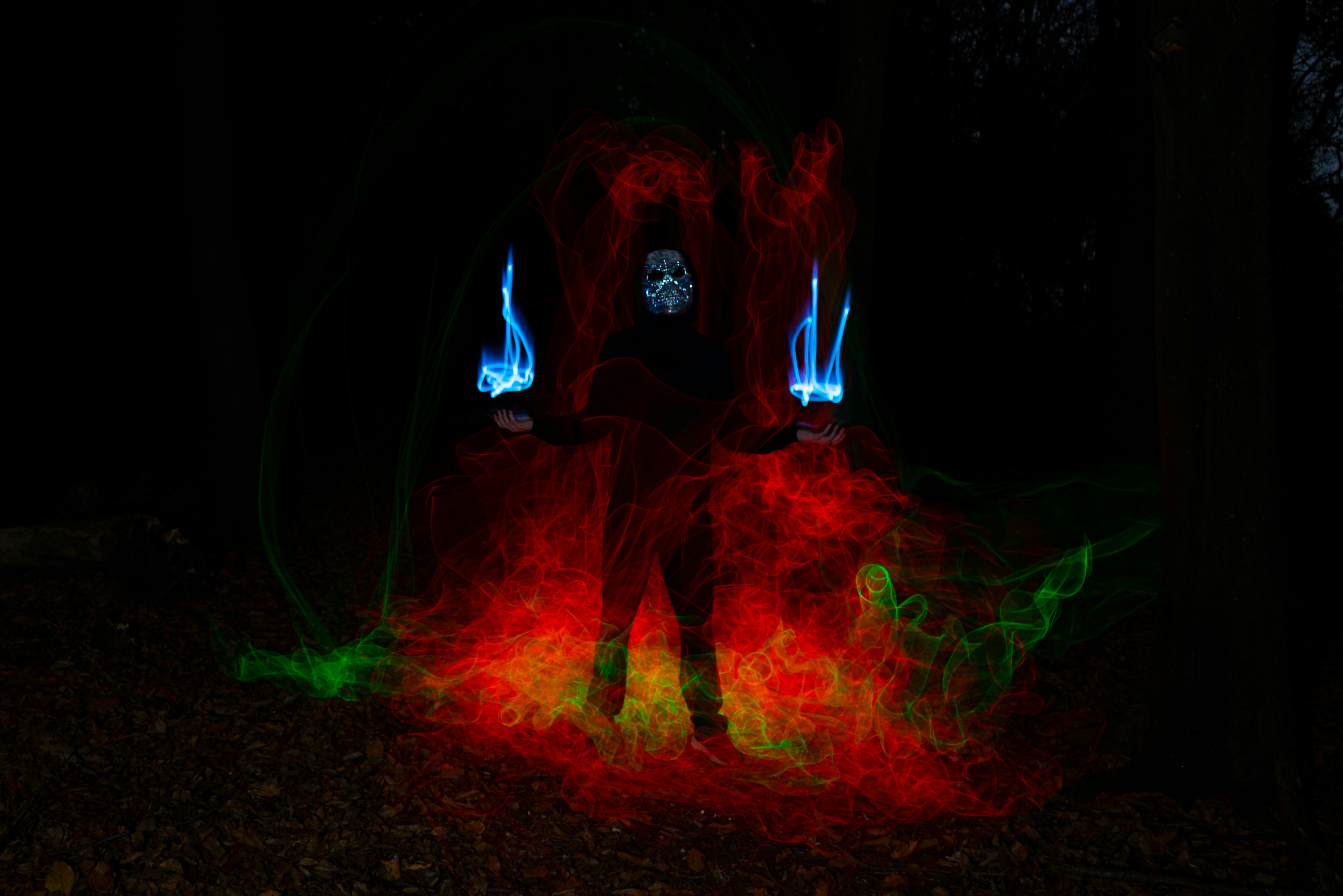 a man standing in a dark forest with red and green lights