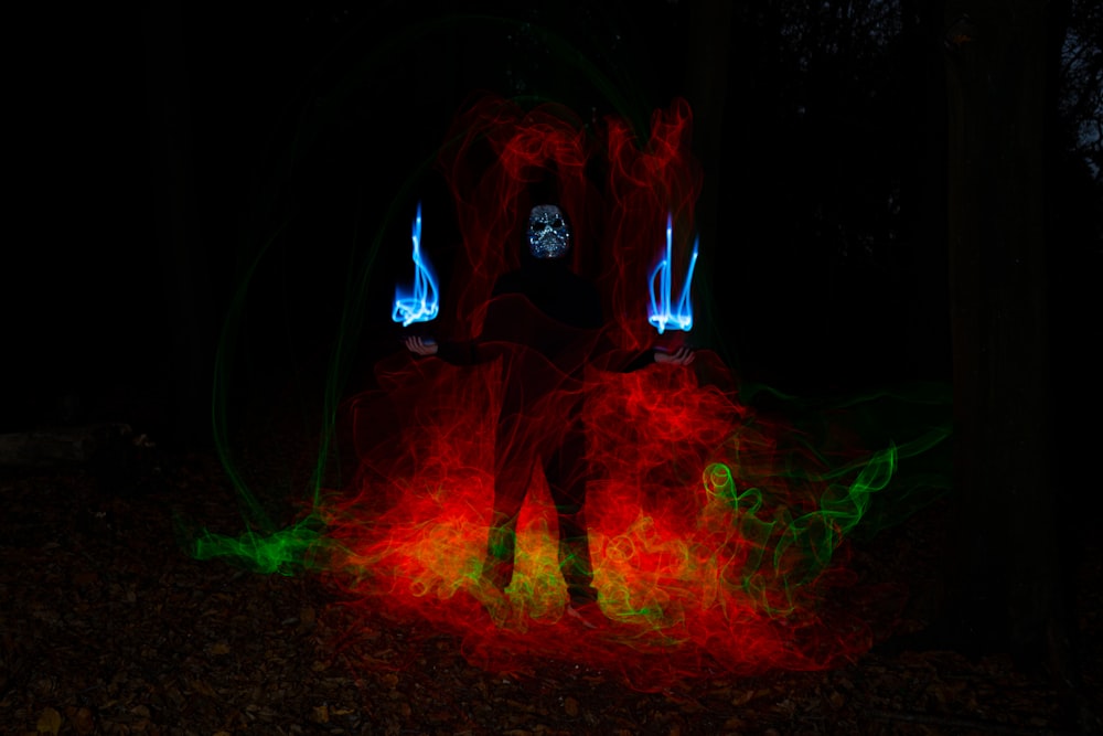 a man standing in a dark forest with red and green lights