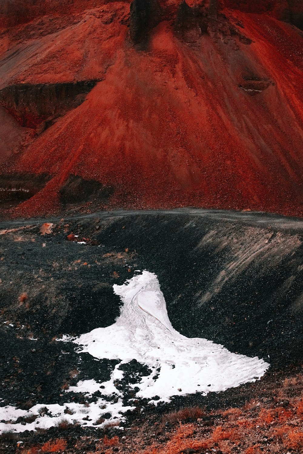 a mountain covered in red dirt and white snow