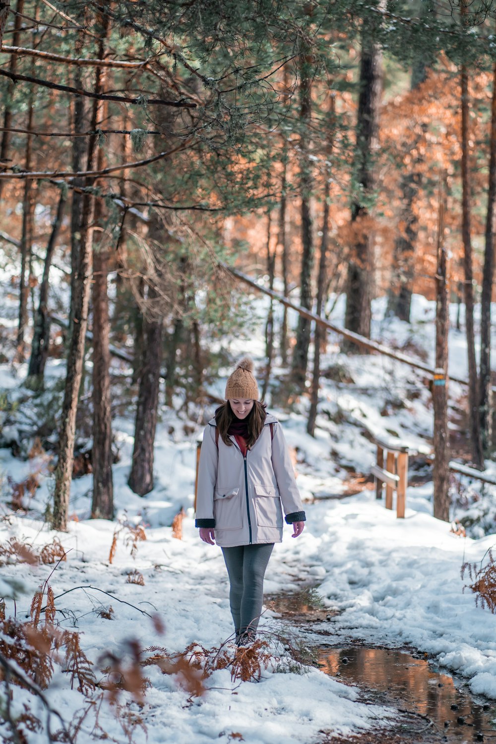 a woman walking through the woods in the snow