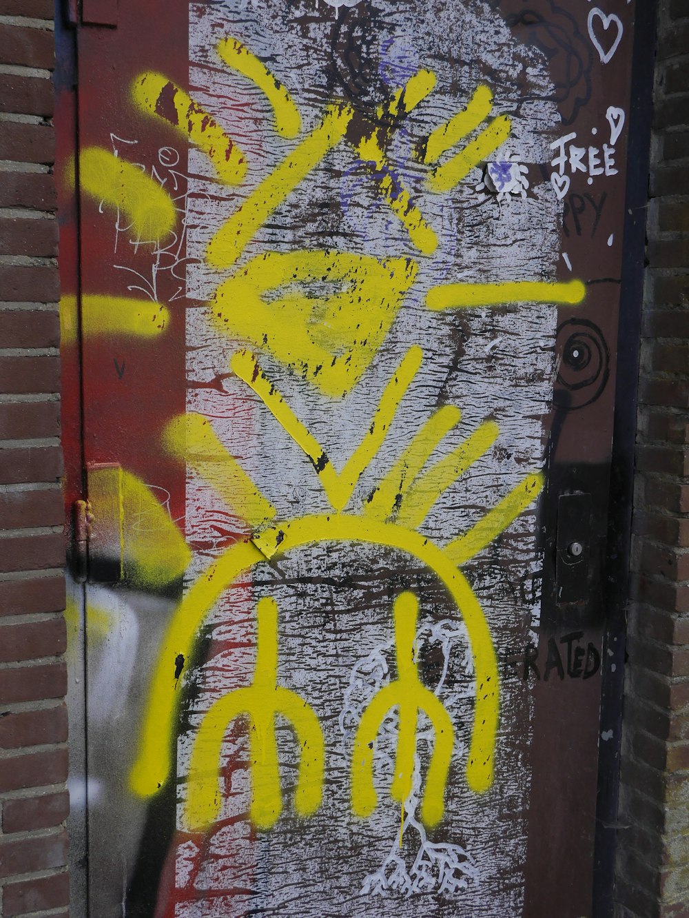 a door with yellow graffiti on it next to a brick wall