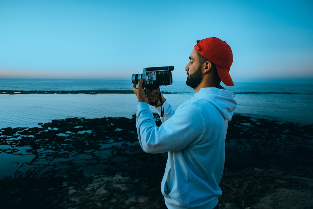 a man taking a picture of the ocean with a camera