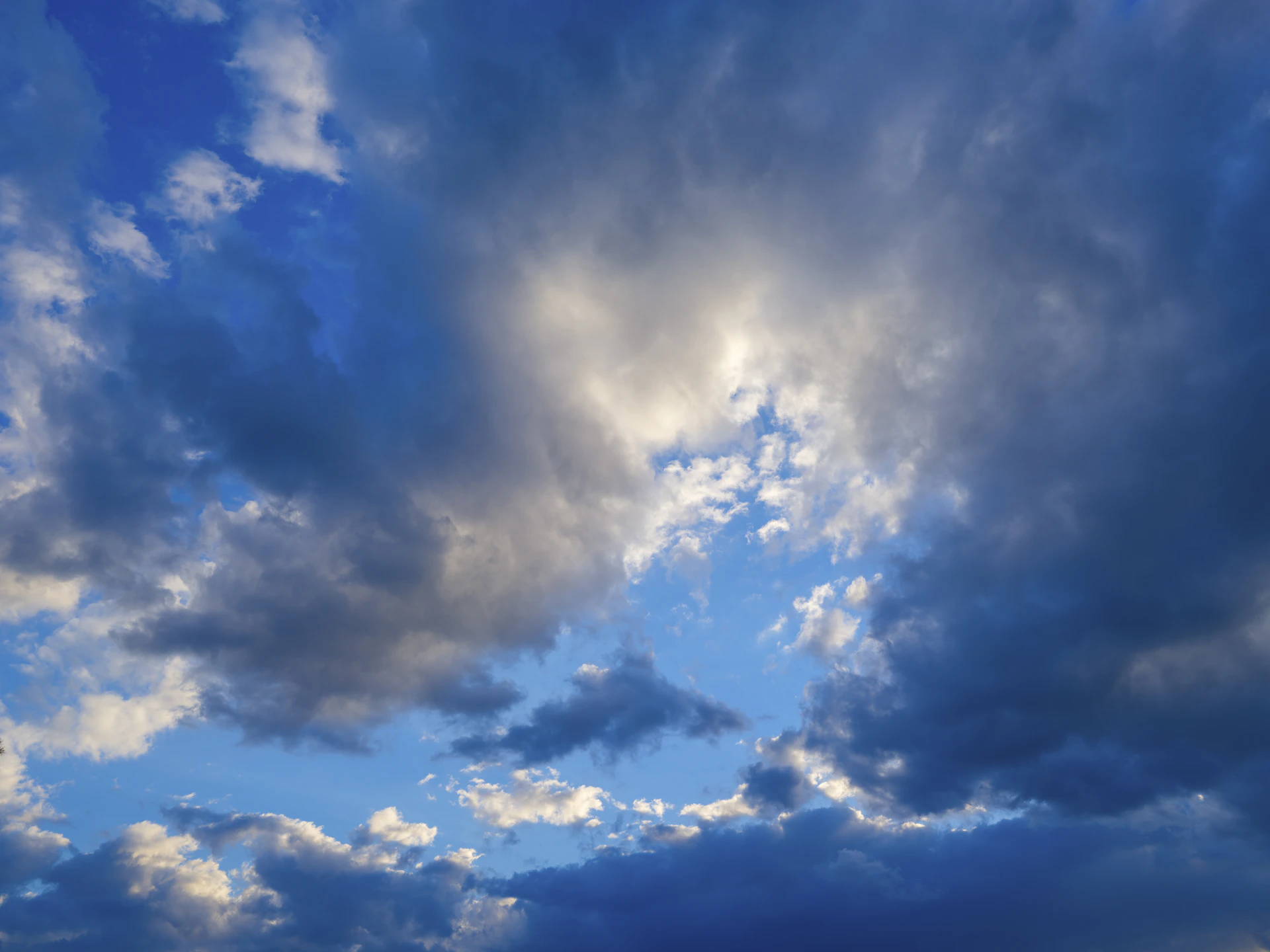 a plane flying through a cloudy blue sky