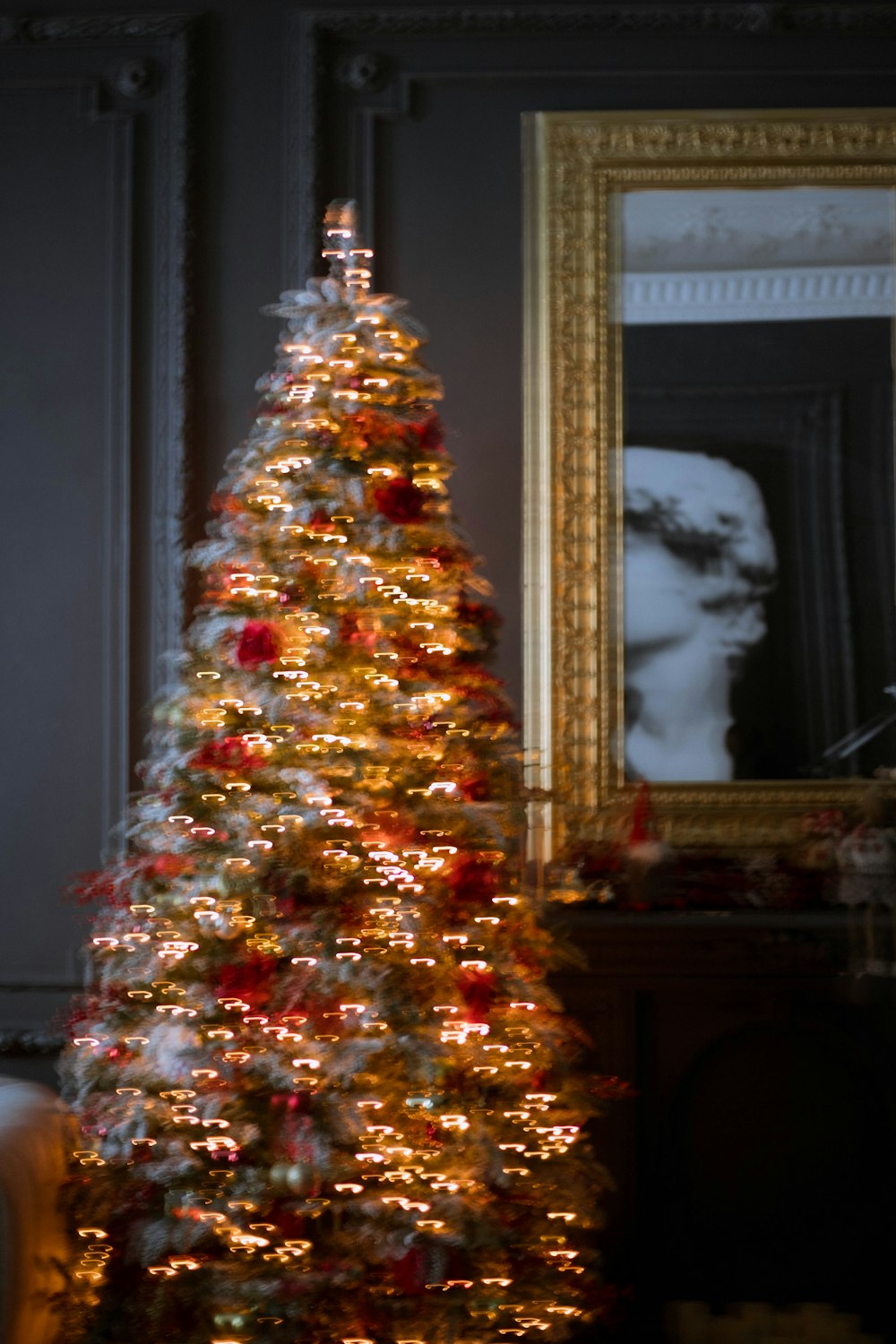 a lit christmas tree in front of a mirror