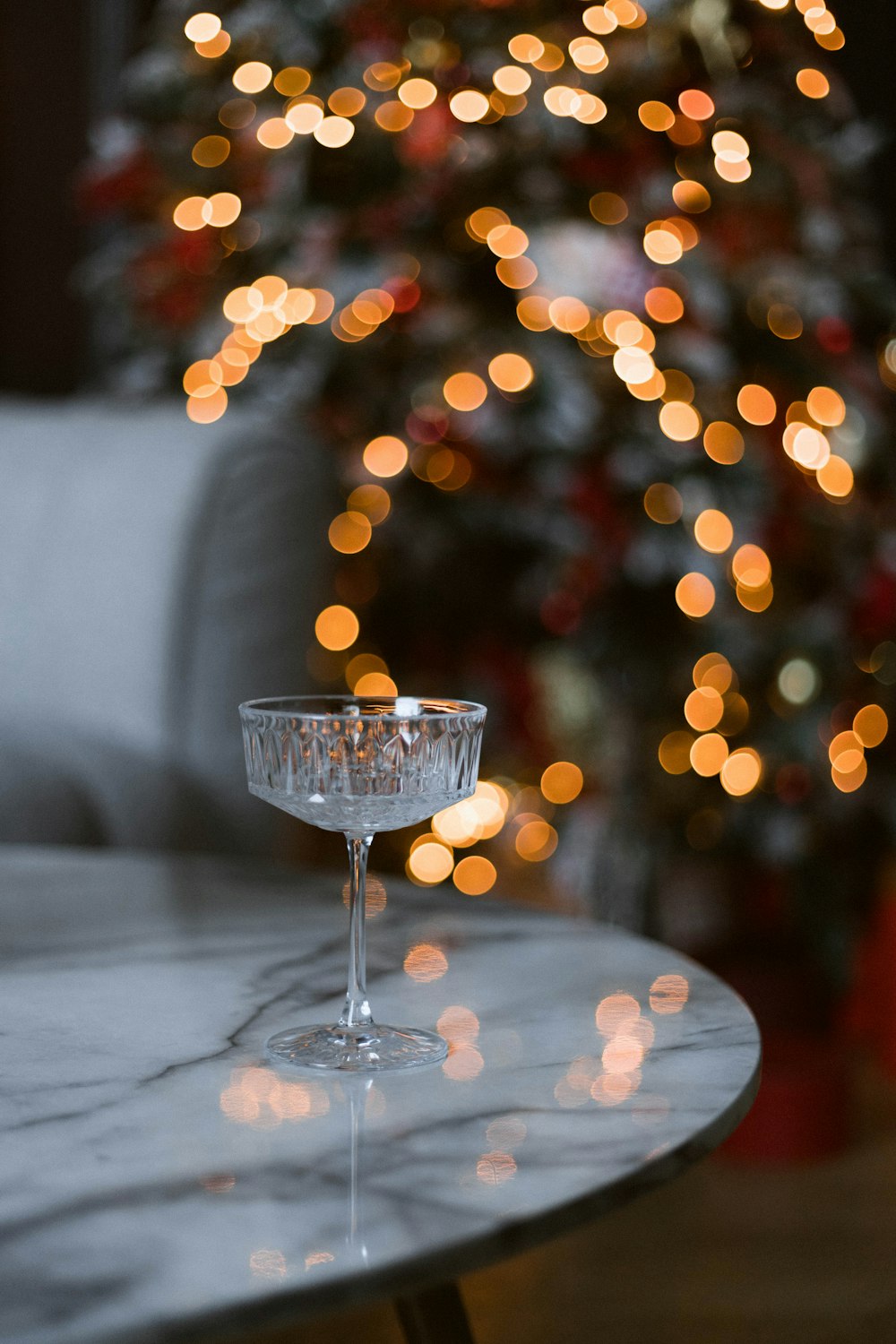 a glass of wine on a table with a christmas tree in the background