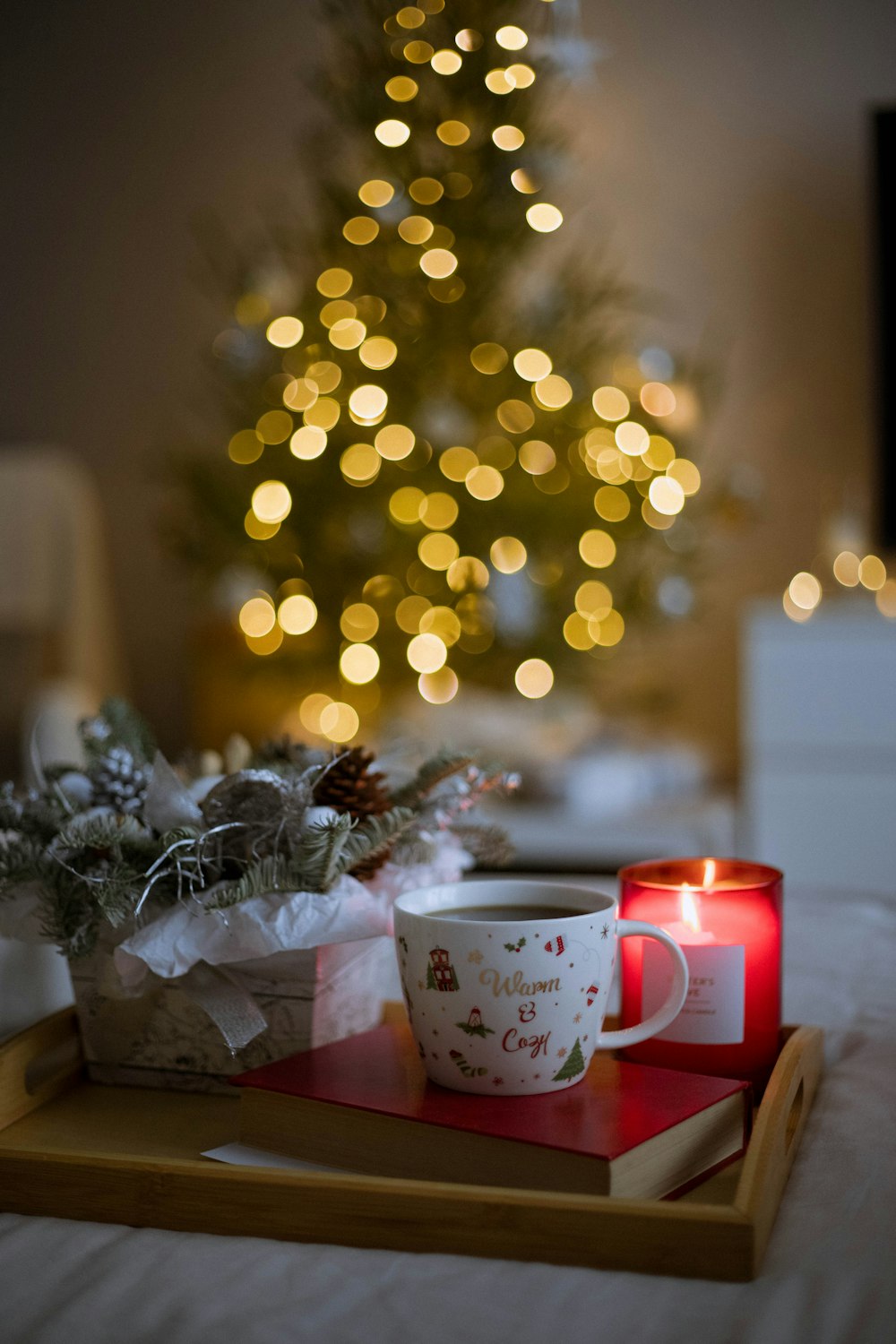 Une tasse de café posée sur un plateau à côté d’un sapin de Noël