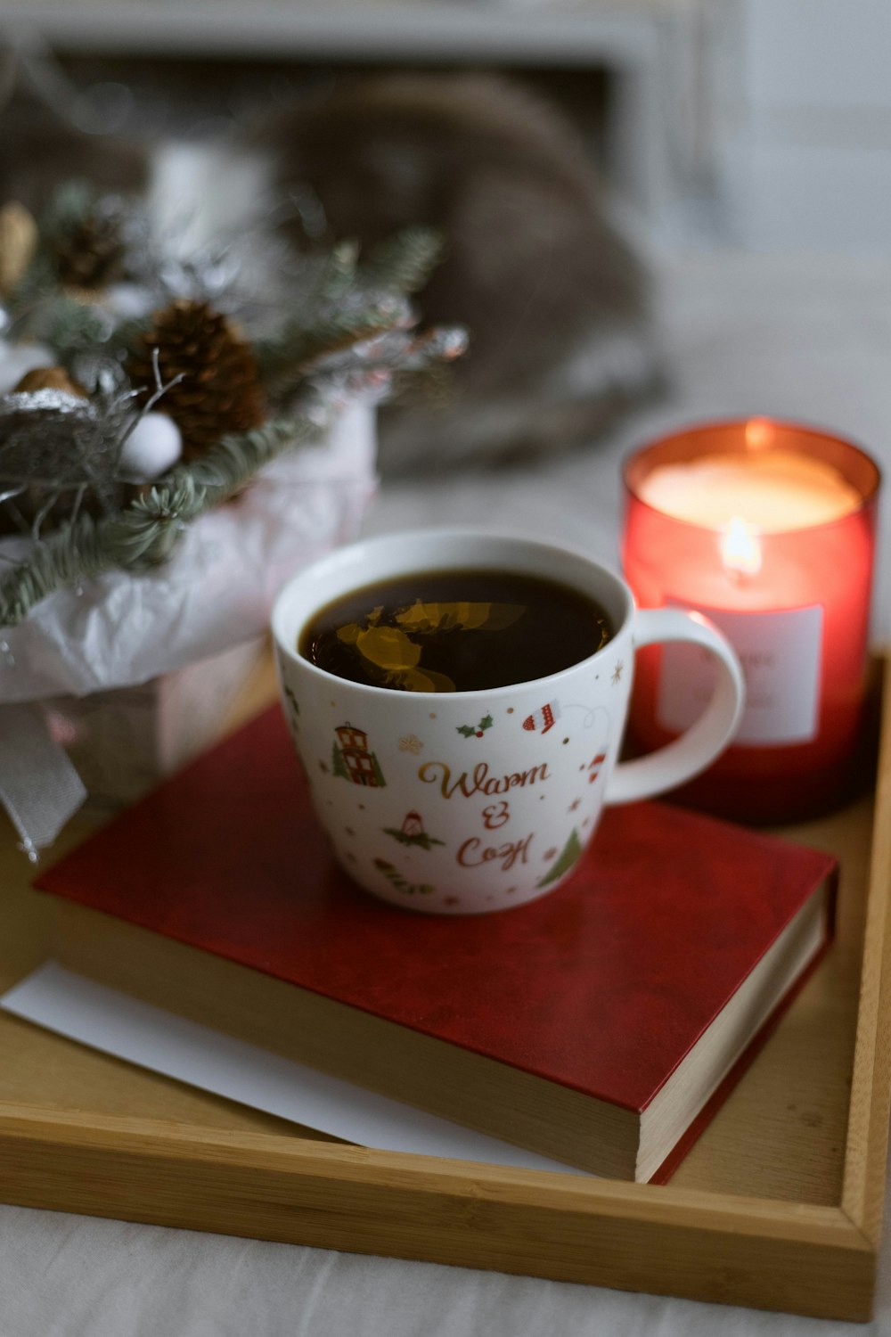 a cup of coffee on a tray next to a candle