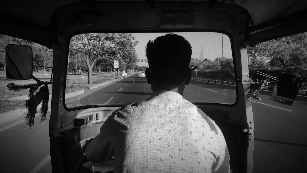 a black and white photo of a man driving a truck