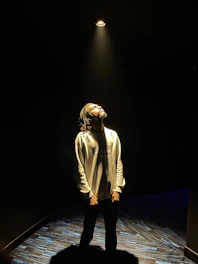 A candid photo of the actress rehearsing on stage under warm spotlight lighting.