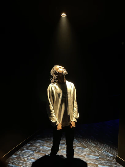 A warm spotlight illuminating a young actor's focused face during rehearsal.