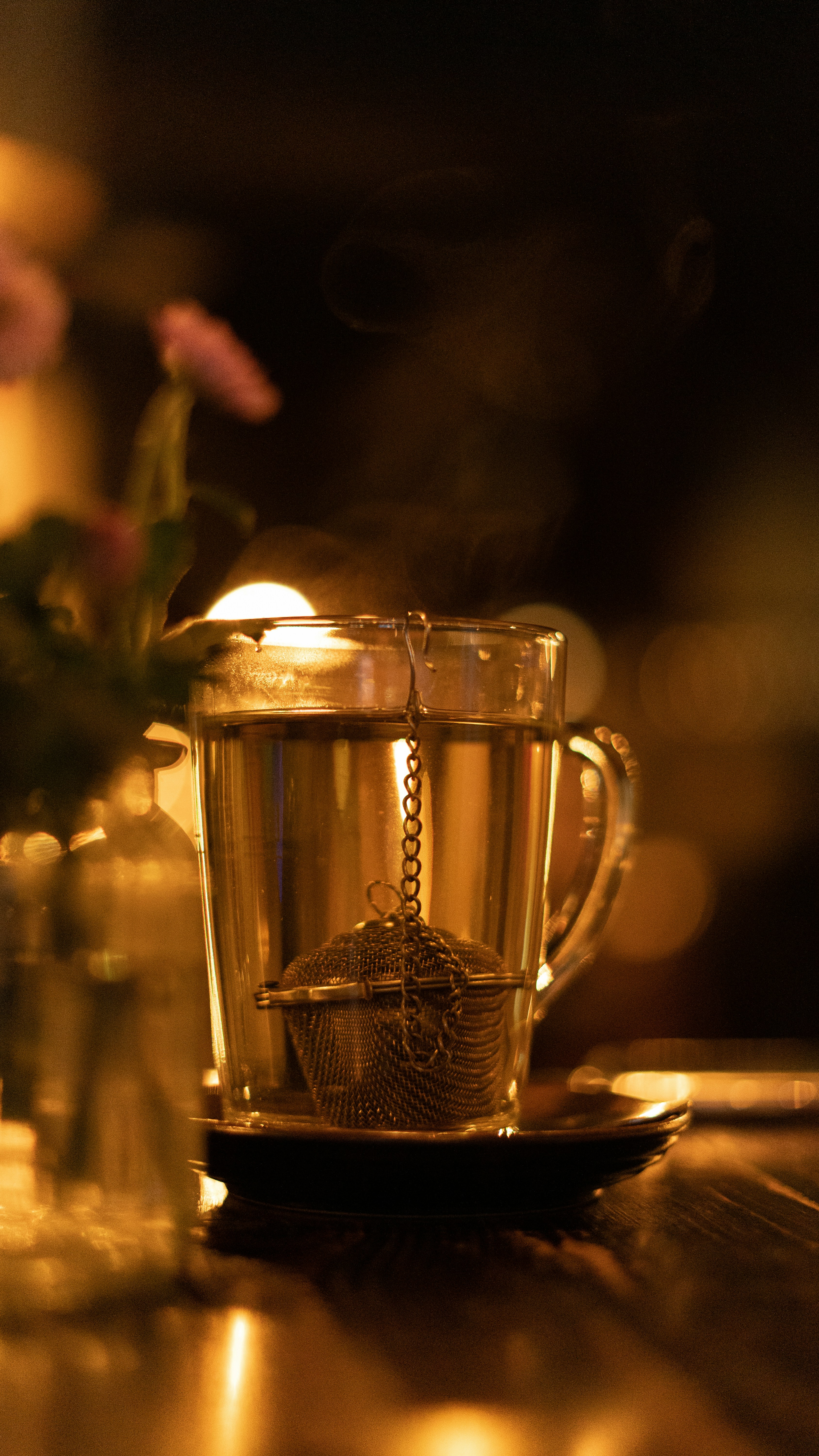 a cup of tea on a table next to a vase of flowers
