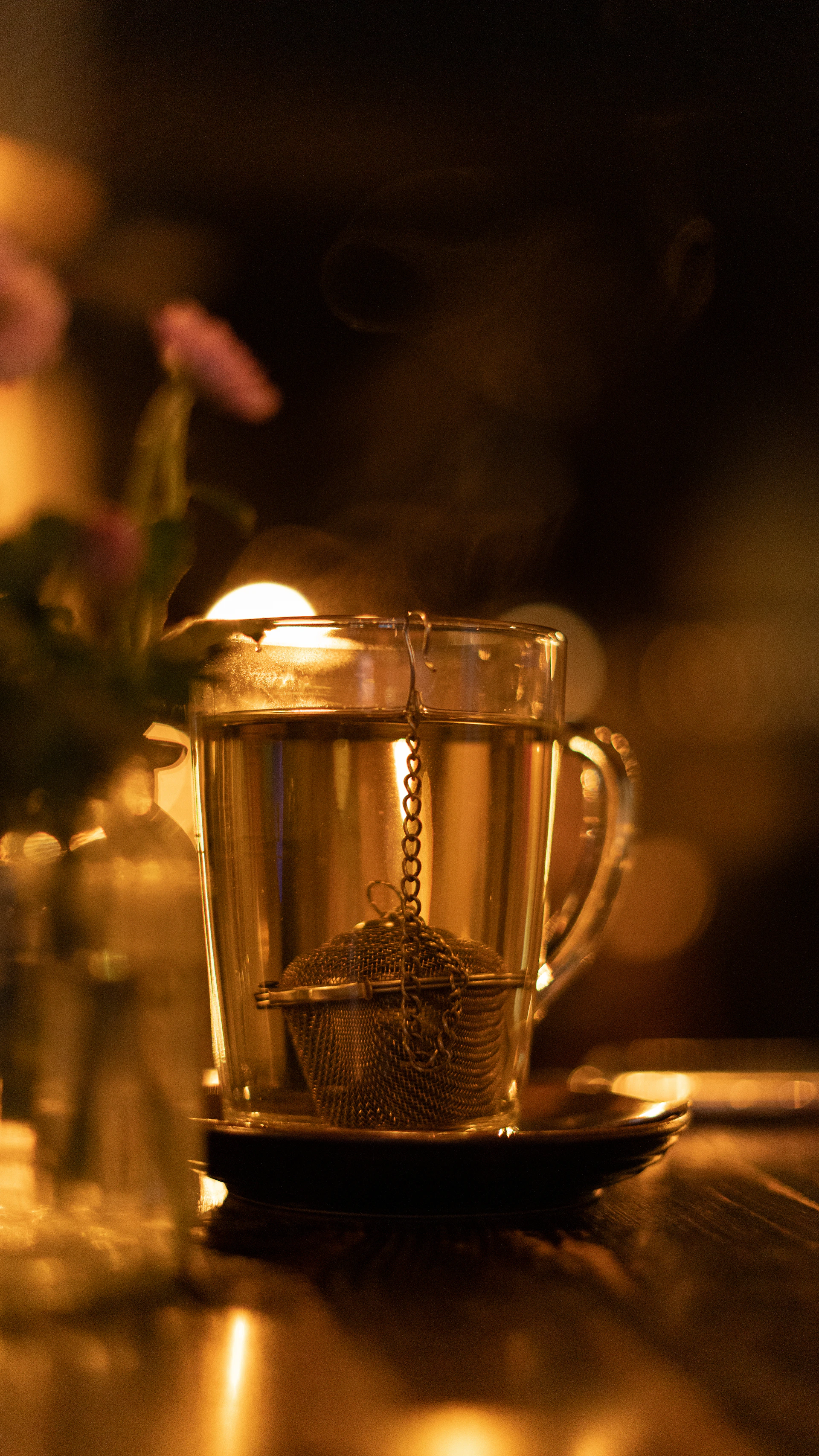 a cup of tea on a table next to a vase of flowers