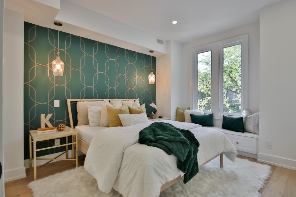 un dormitorio con una pared verde y una cama blanca