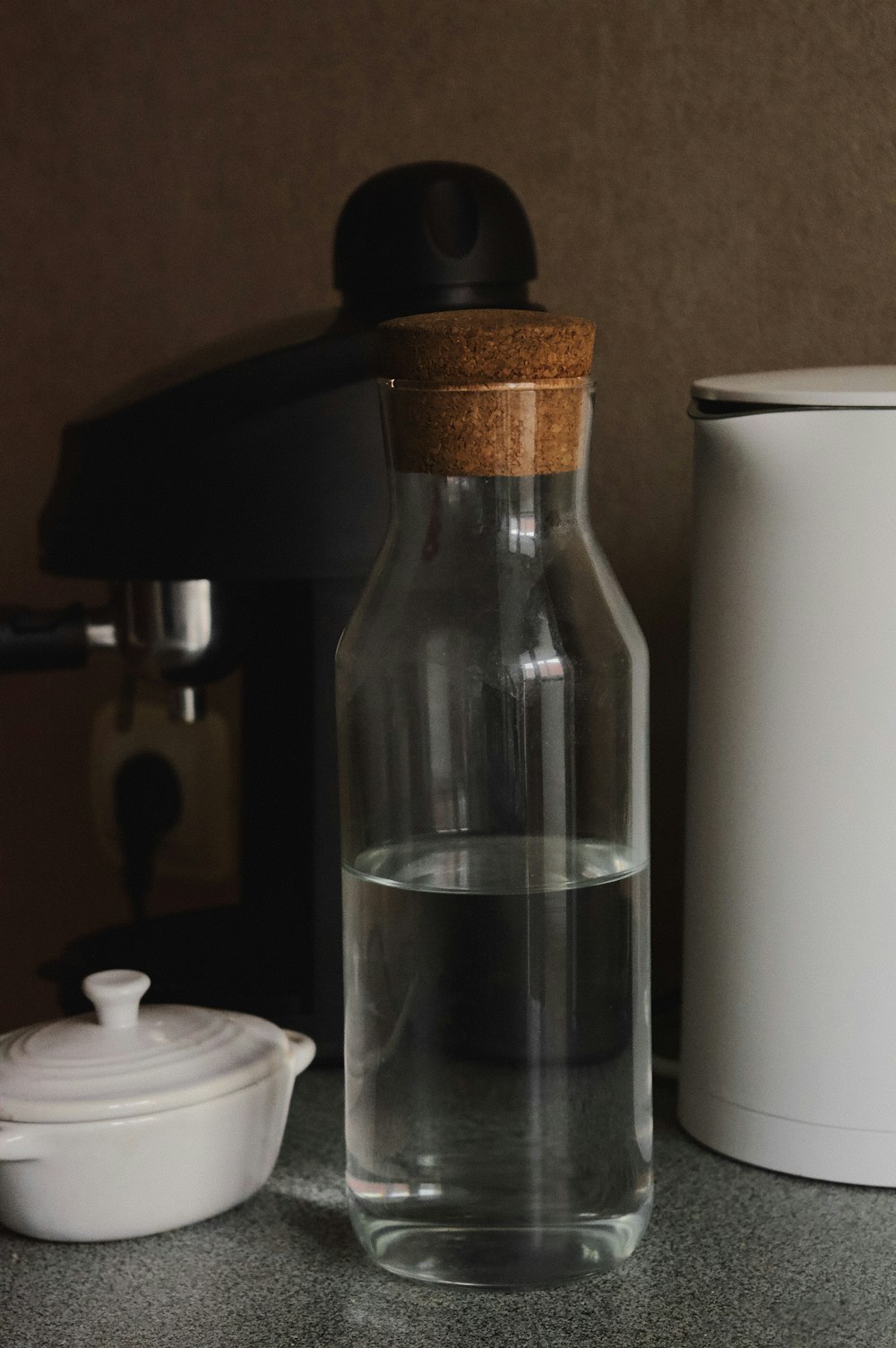 Una botella de agua sentada en un mostrador junto a un recipiente