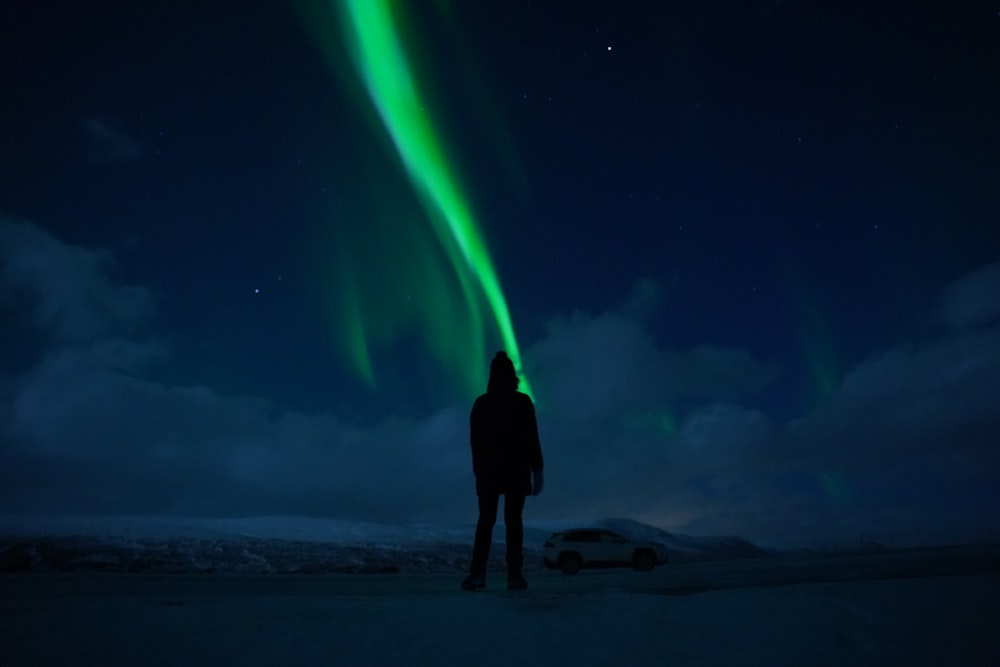a person standing in the snow looking at the aurora bore