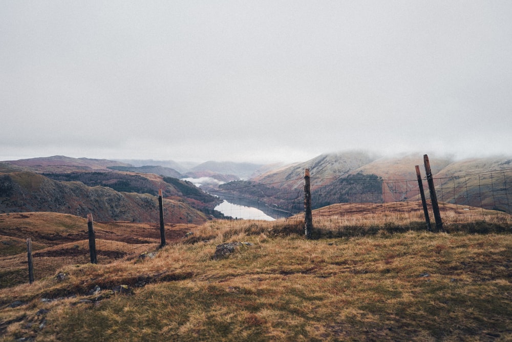 a field with a fence and mountains in the background