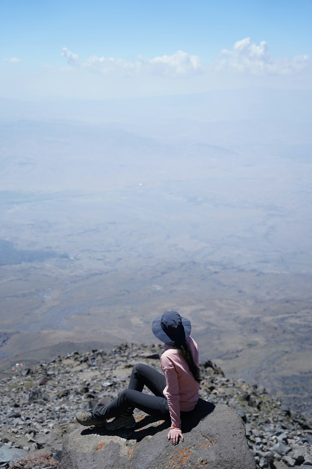 a woman sitting on top of a large rock