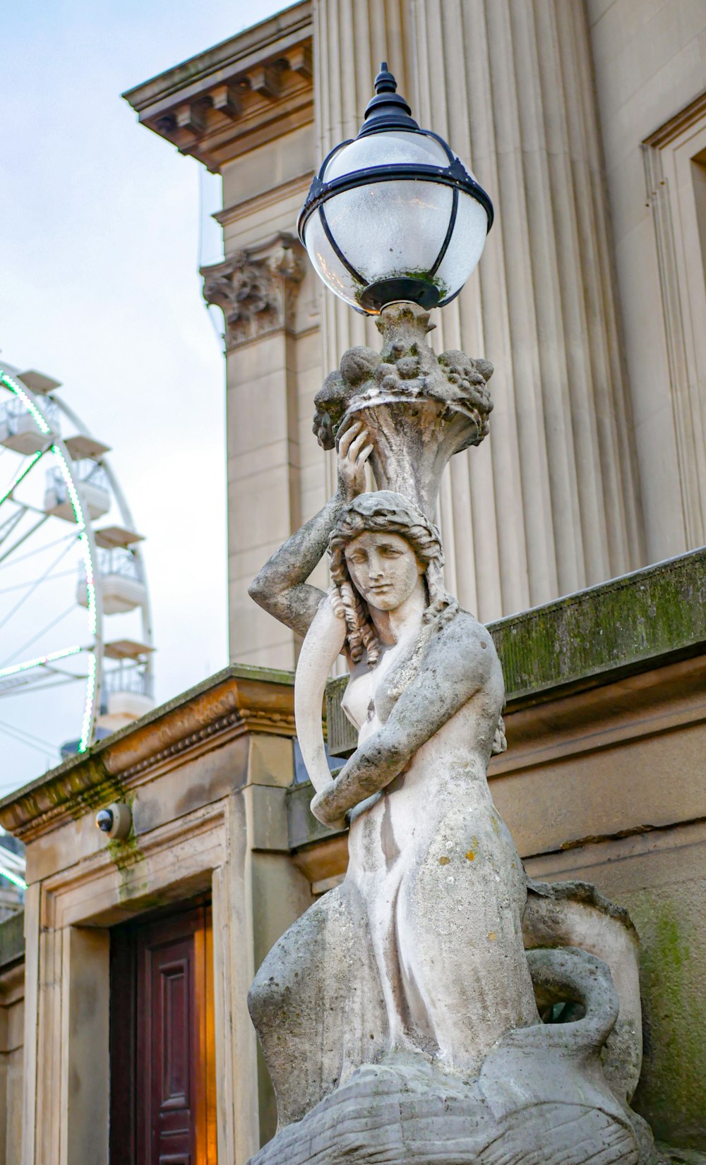 a statue of a woman with a hat on top of a fountain
