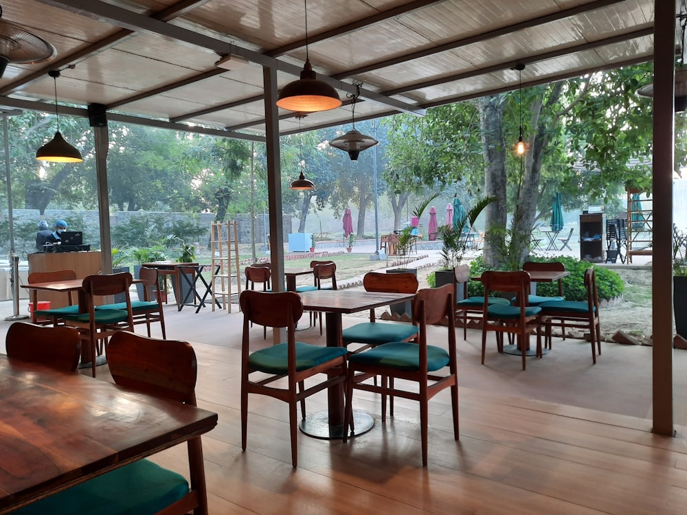 a restaurant with wooden tables and chairs and green cushions