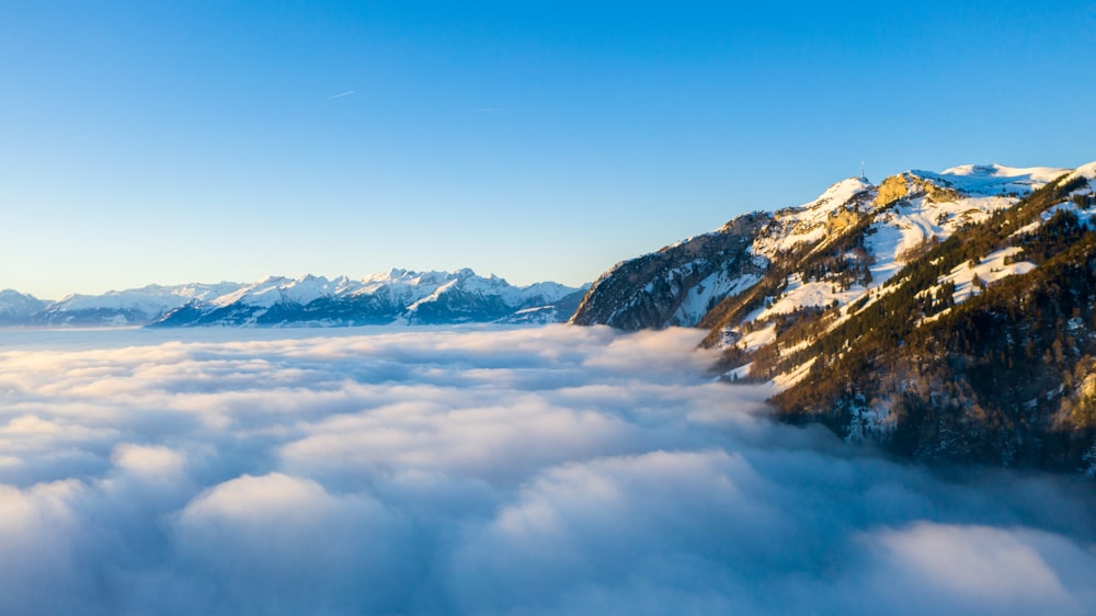 a mountain covered in snow and surrounded by clouds