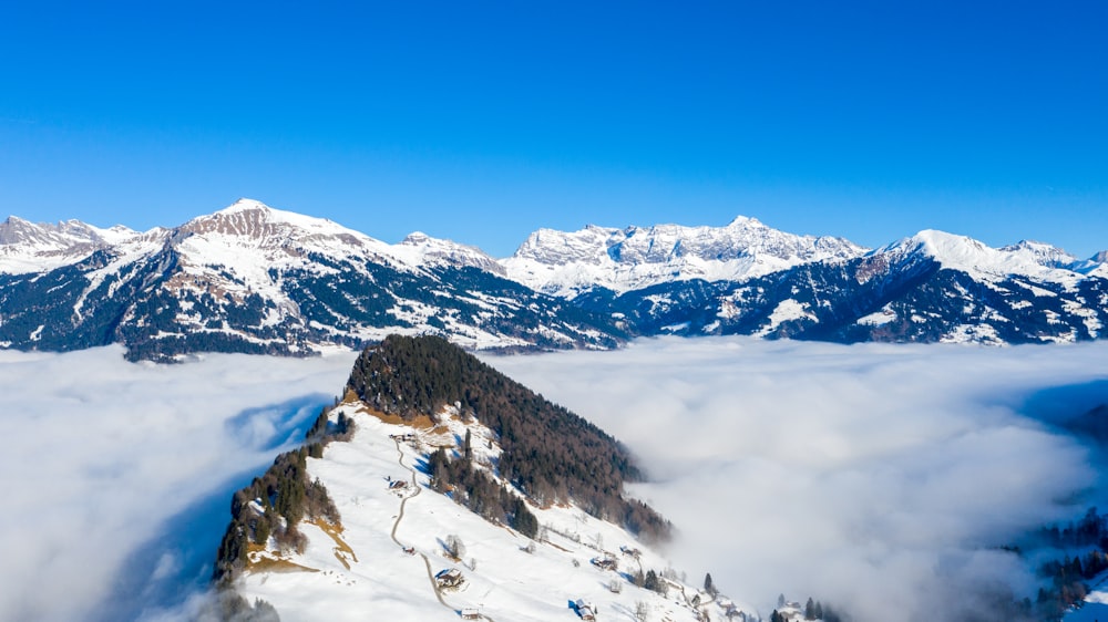 a mountain covered in snow and clouds under a blue sky