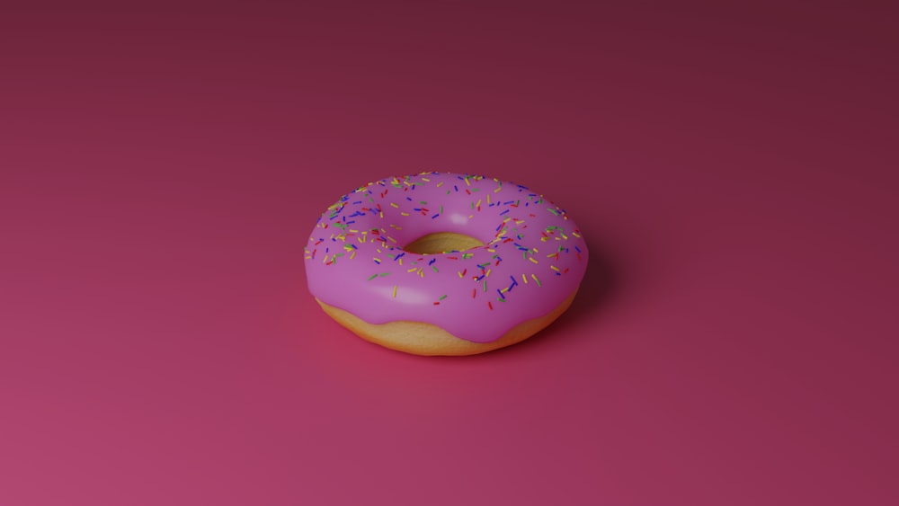 a pink donut with sprinkles on a pink background
