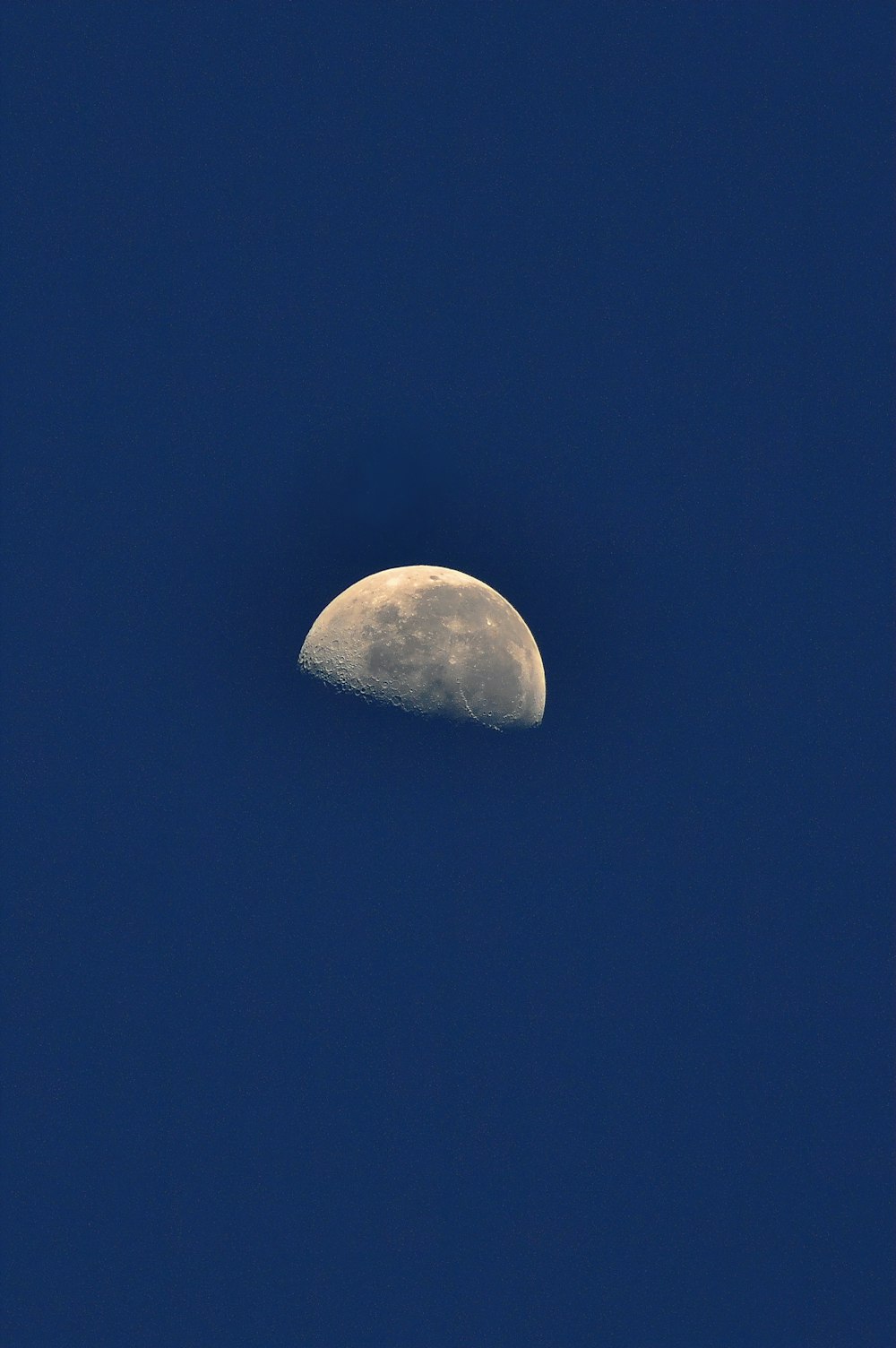 Una mezza luna è vista nel cielo blu