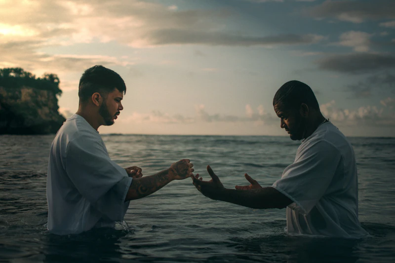 Two people wading into open water for a baptism