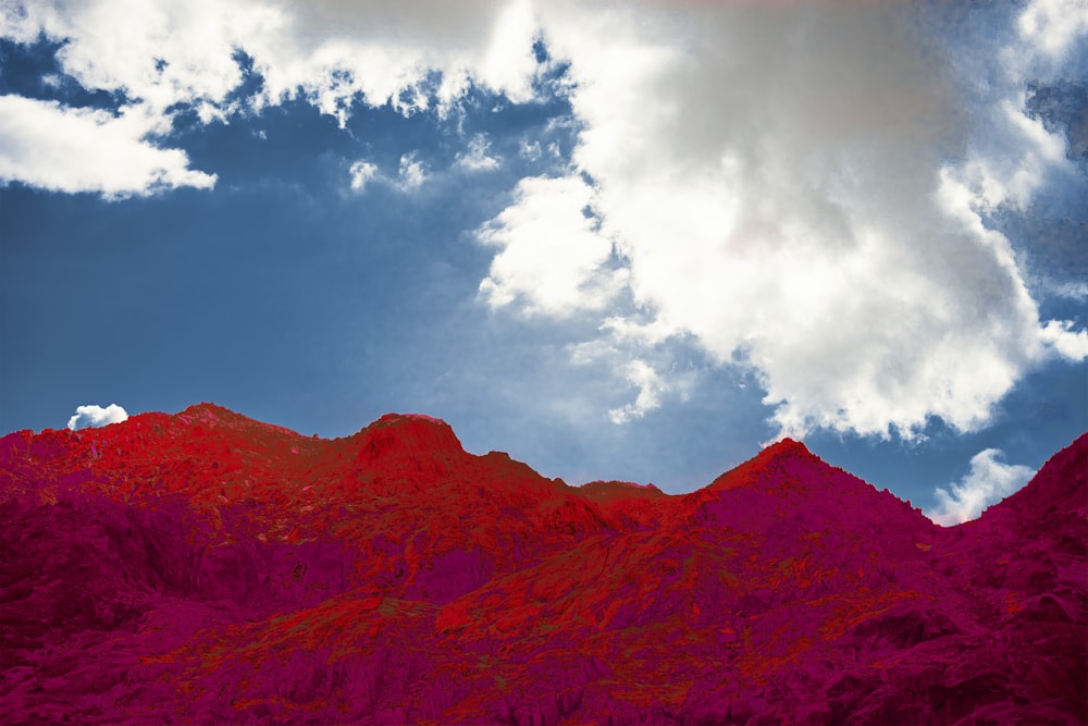 a red mountain under a cloudy blue sky