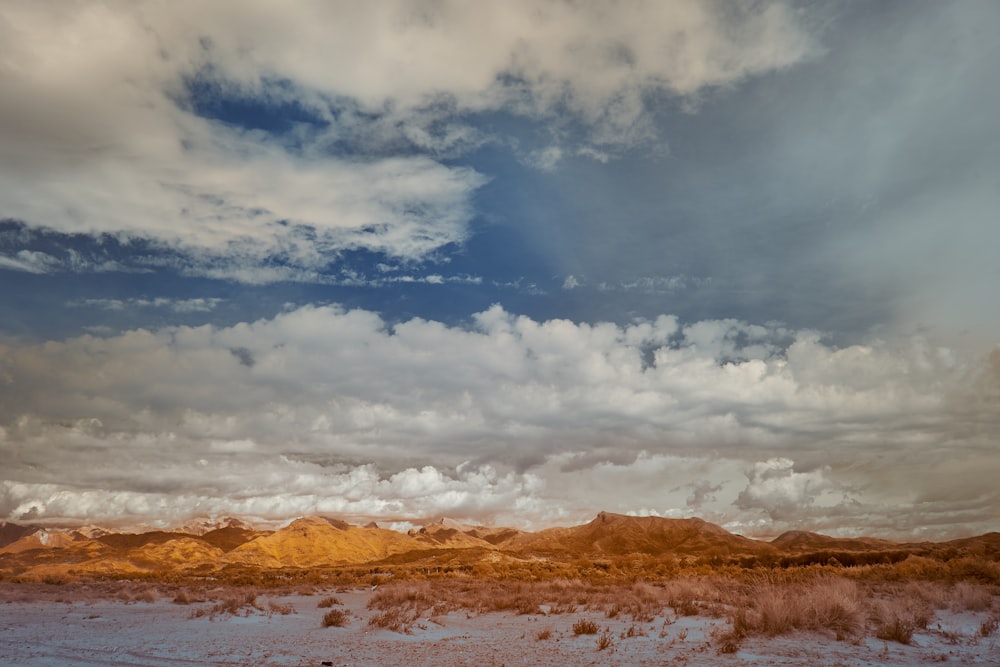 a desert landscape with a few clouds in the sky
