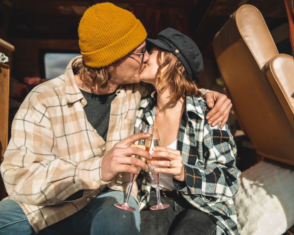 a man and a woman kissing while holding wine glasses
