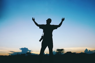 a silhouette of a man raising his arms in the air