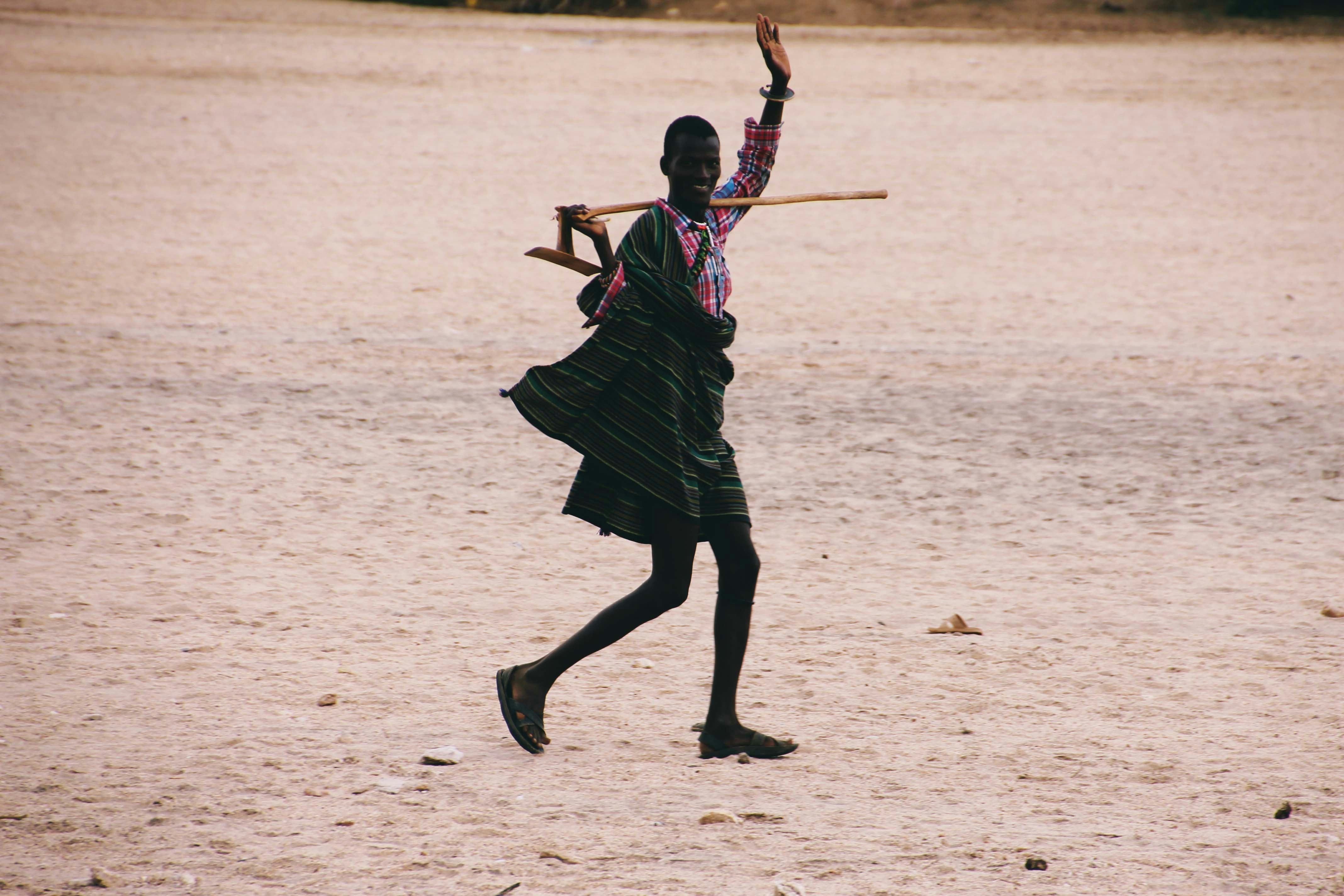 A Turkana man smiles and weaves at the camera as walks away