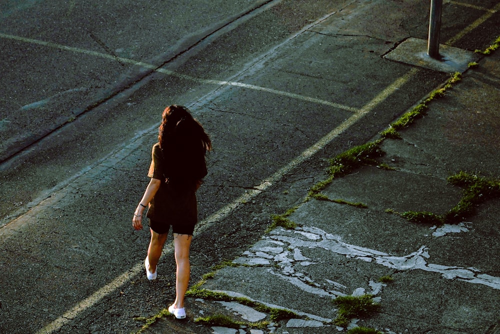 a woman walking down a street next to a street sign