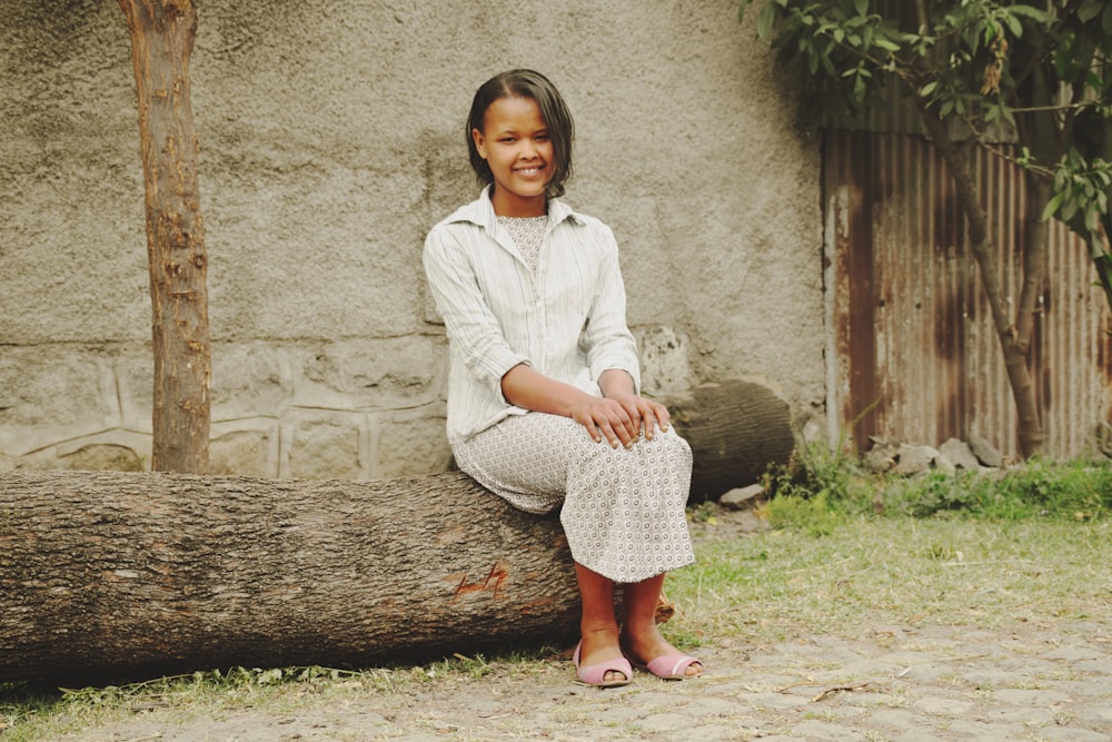 a woman sitting on top of a tree log