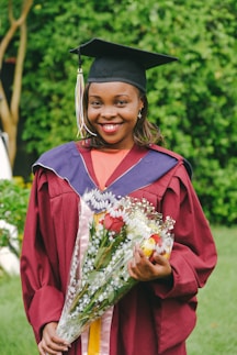a woman in a graduation gown holding a bouquet of flowers