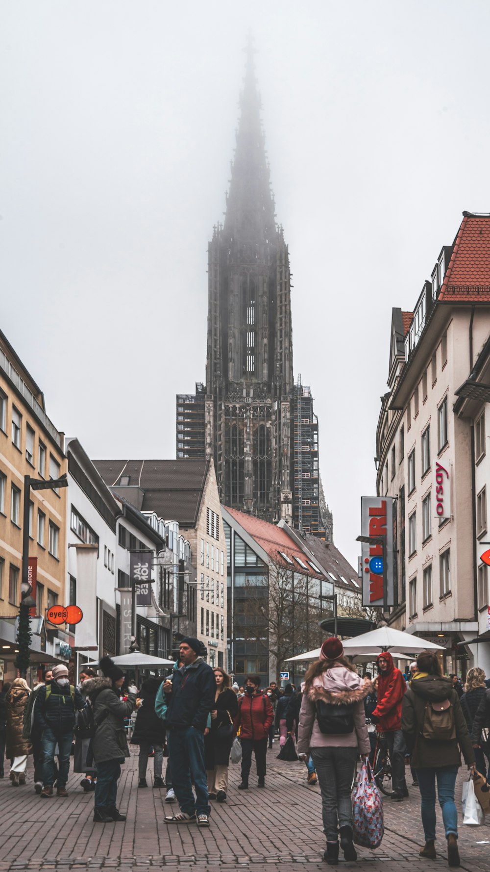 a group of people walking down a street next to tall buildings