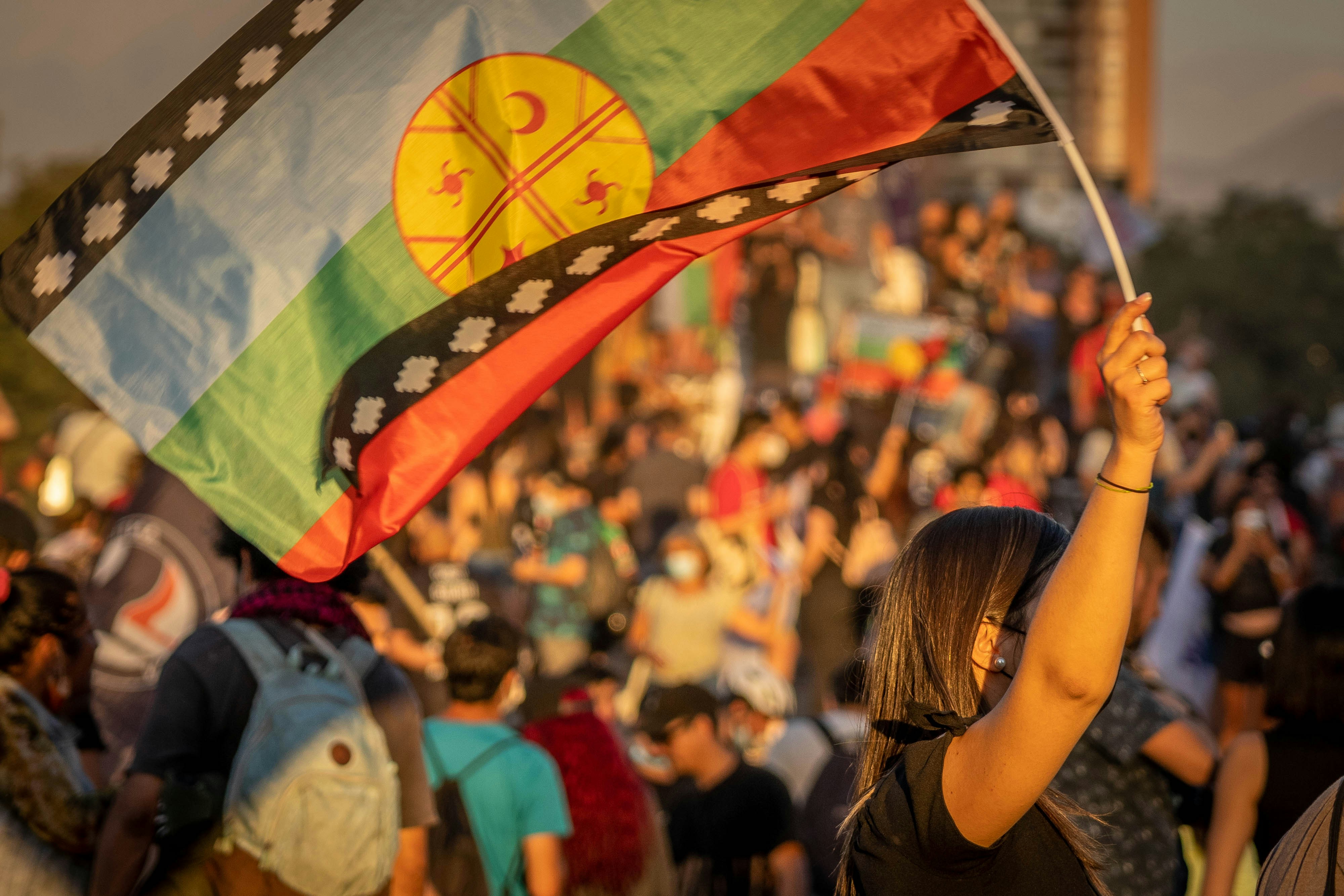 Une femme tenant un drapeau devant une foule