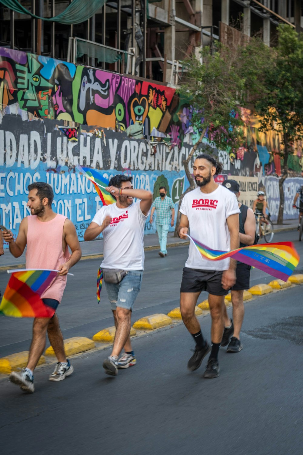 虹色の旗を持って通りを歩く人々のグループ