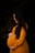 a pregnant woman in a yellow dress poses for a photo
