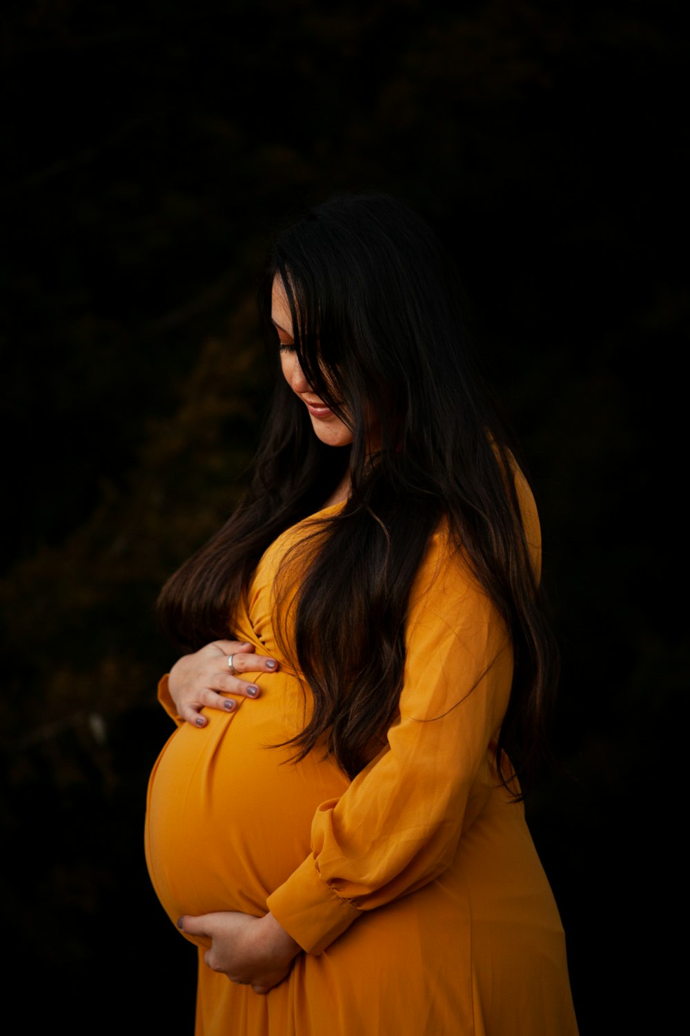 Eine schwangere Frau in einem gelben Kleid posiert für ein Foto
