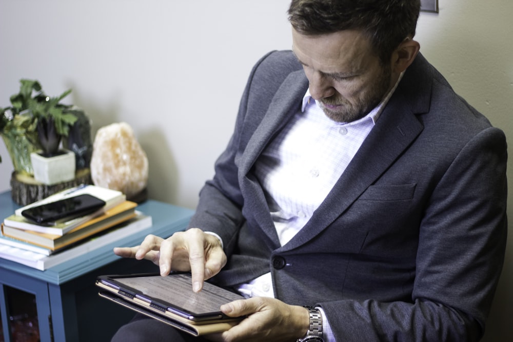 a man in a suit is holding a tablet