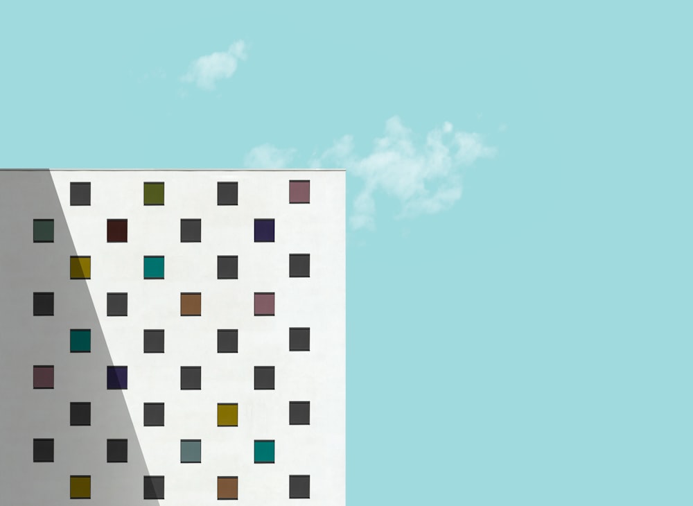 a tall white building with multicolored squares on it