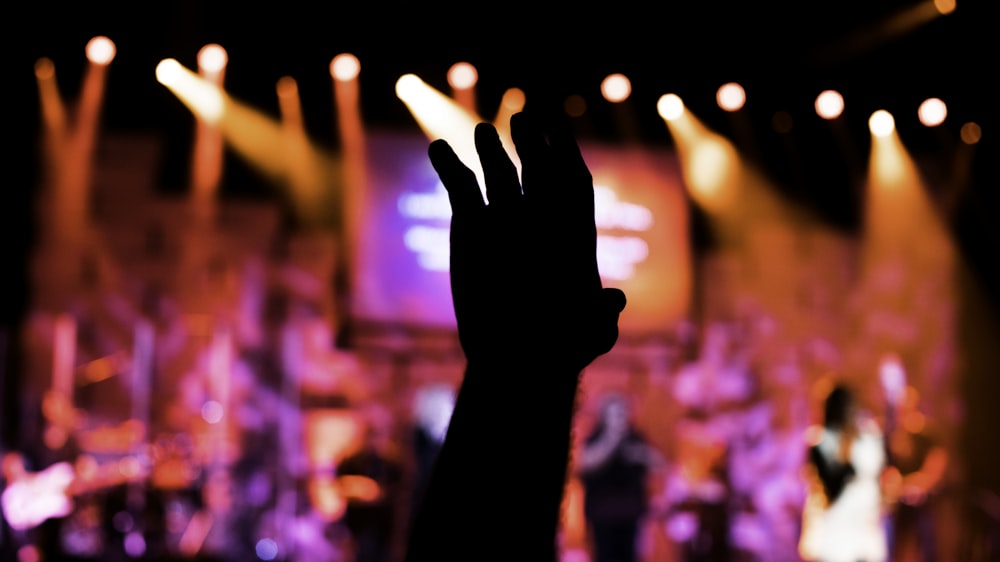 a person raising their hand in front of a stage