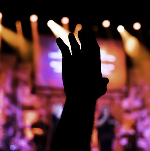 a person raising their hand in front of a stage