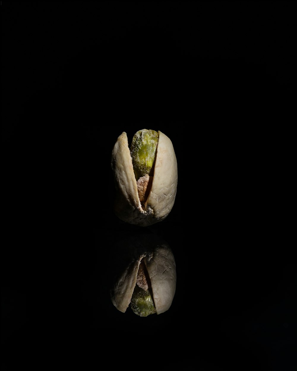 a pistachio on a black background with a reflection
